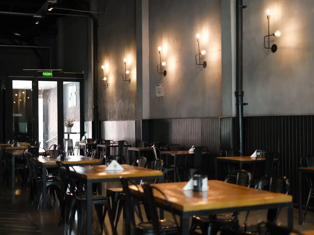 Salón interior con mesas de madera y apliques de luz cálida